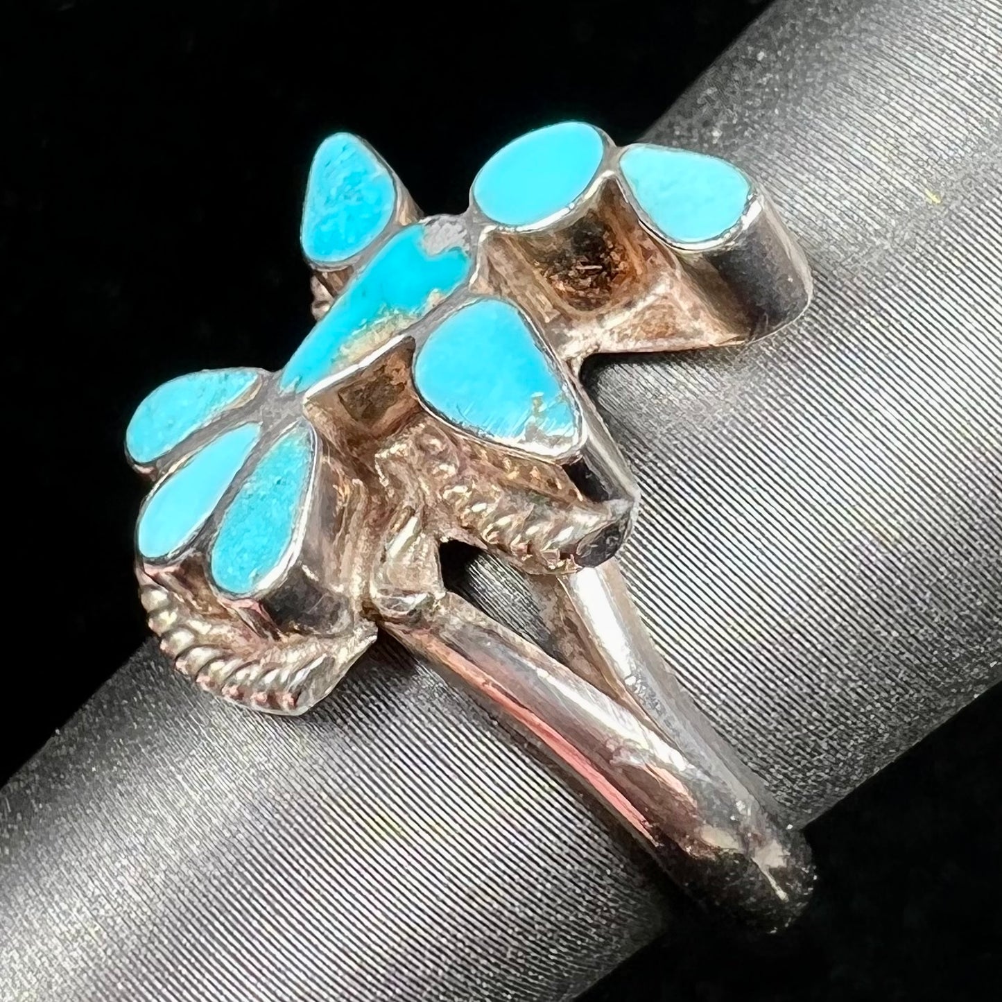 A sterling silver and turquoise inlay ring.  The ring is in the shape of a Native American thunderbird.