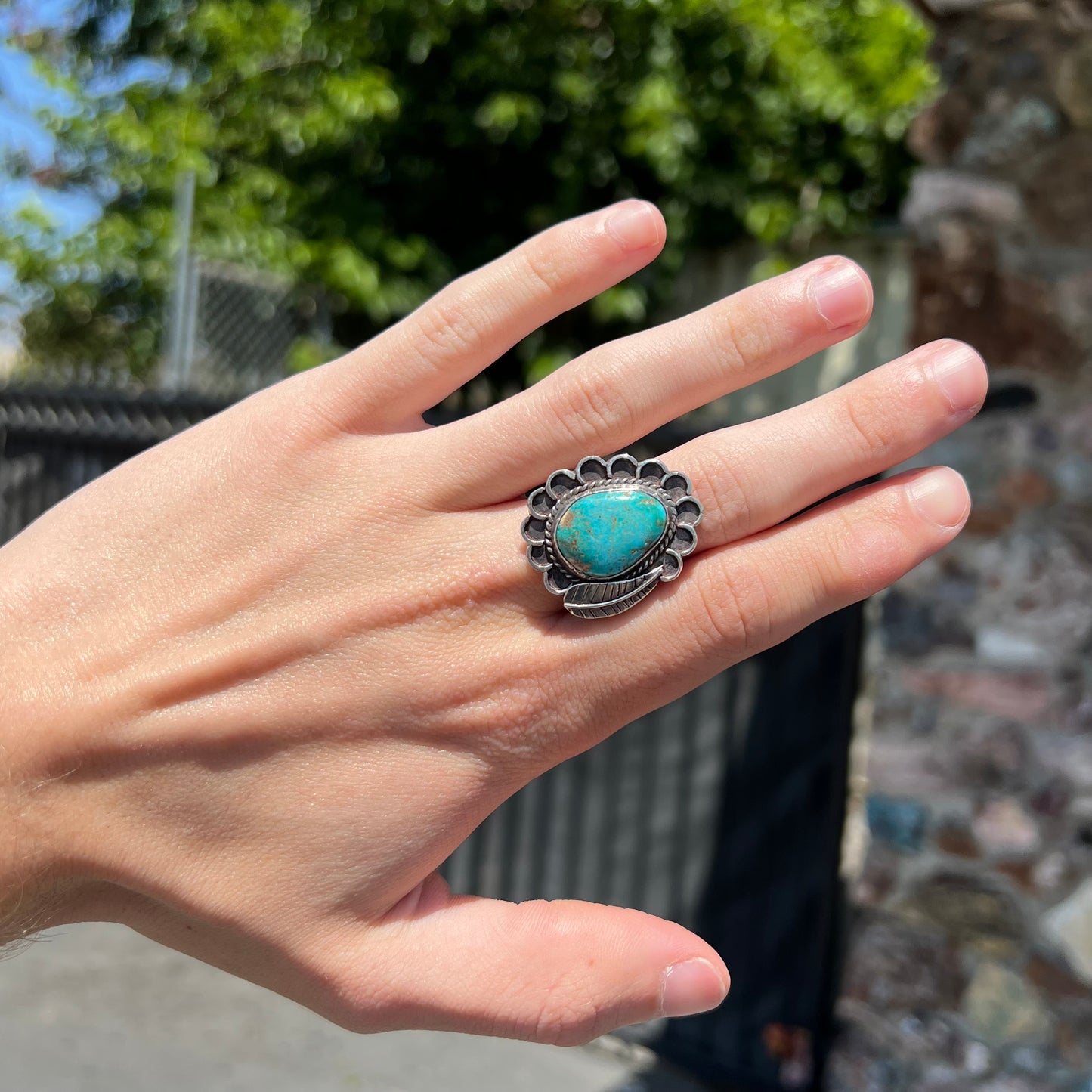 A sterling silver Navajo style ring.  The ring is set with a turquoise stone from Pilot Mountain.  There is a feather decoration next to the stone.