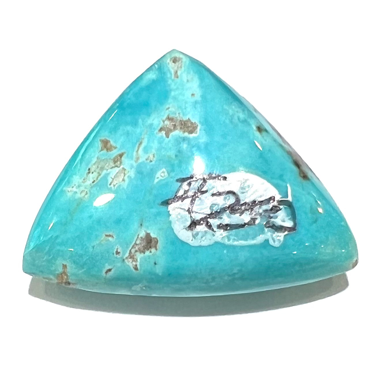 A loose triangular cabochon cut blue turquoise stone from the Sleeping Beauty Mine in Arizona.