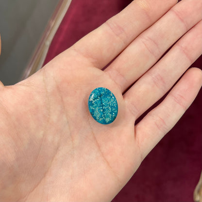 A loose, oval cabochon cut turquoise stone from Morenci, Arizona.  The stone has azurite inclusions.