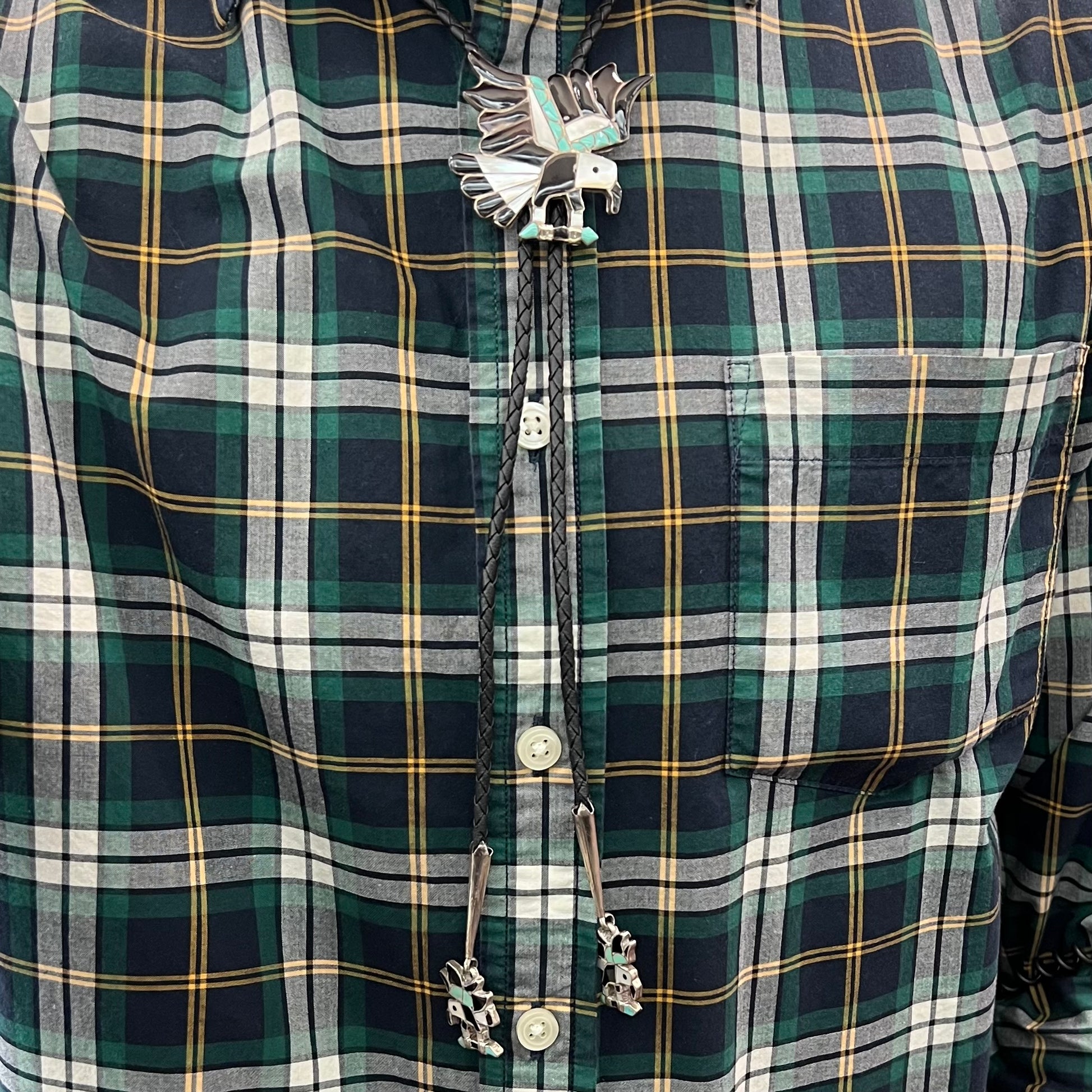 A sterling silver Zuni Indian-made bolo tie featuring the motif of three flying eagles inlaid with natural stones.