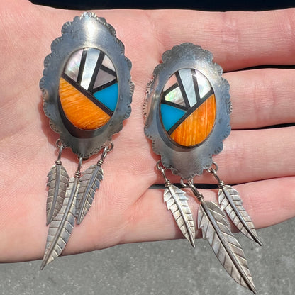 A pair of Native American style feather dangle earrings inlaid with mother of pearl shell and turquoise.