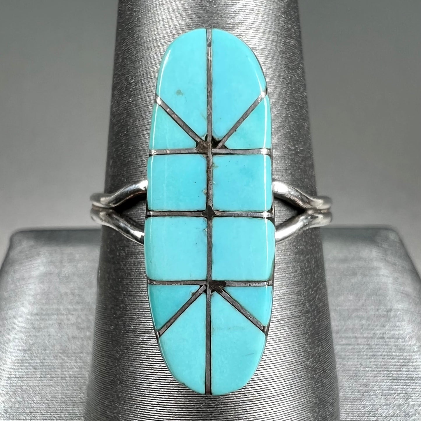 A handmade silver turquoise ring inlaid with six pieces of Sleeping Beauty turquoise.  The back of the ring is signed "FT".