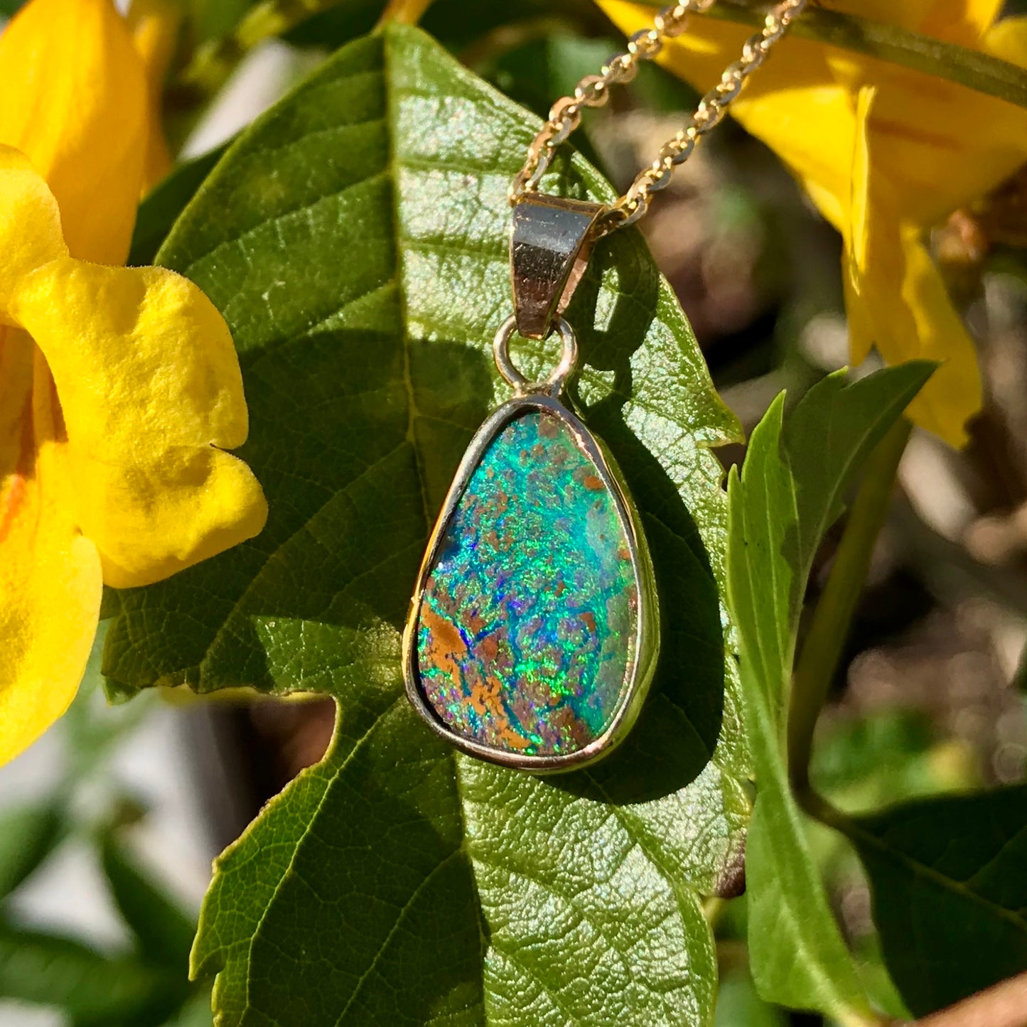 Green and blue Queensland boulder opal pendant in 14k yellow gold on cable chain.