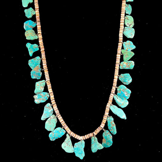 A Santo Domingo puka shell bead necklace with drilled turquoise nuggets attached.