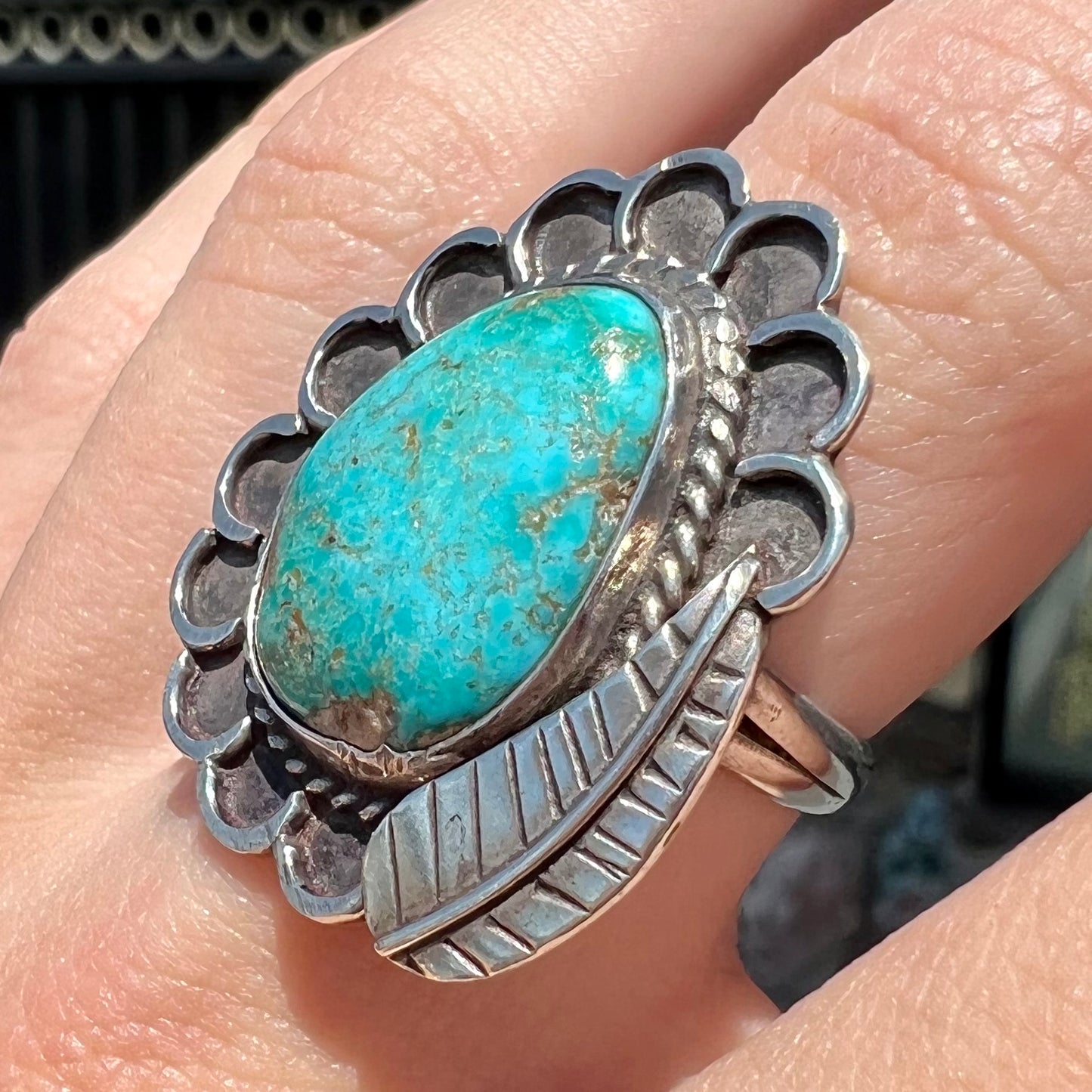 A sterling silver Navajo style ring.  The ring is set with a turquoise stone from Pilot Mountain.  There is a feather decoration next to the stone.