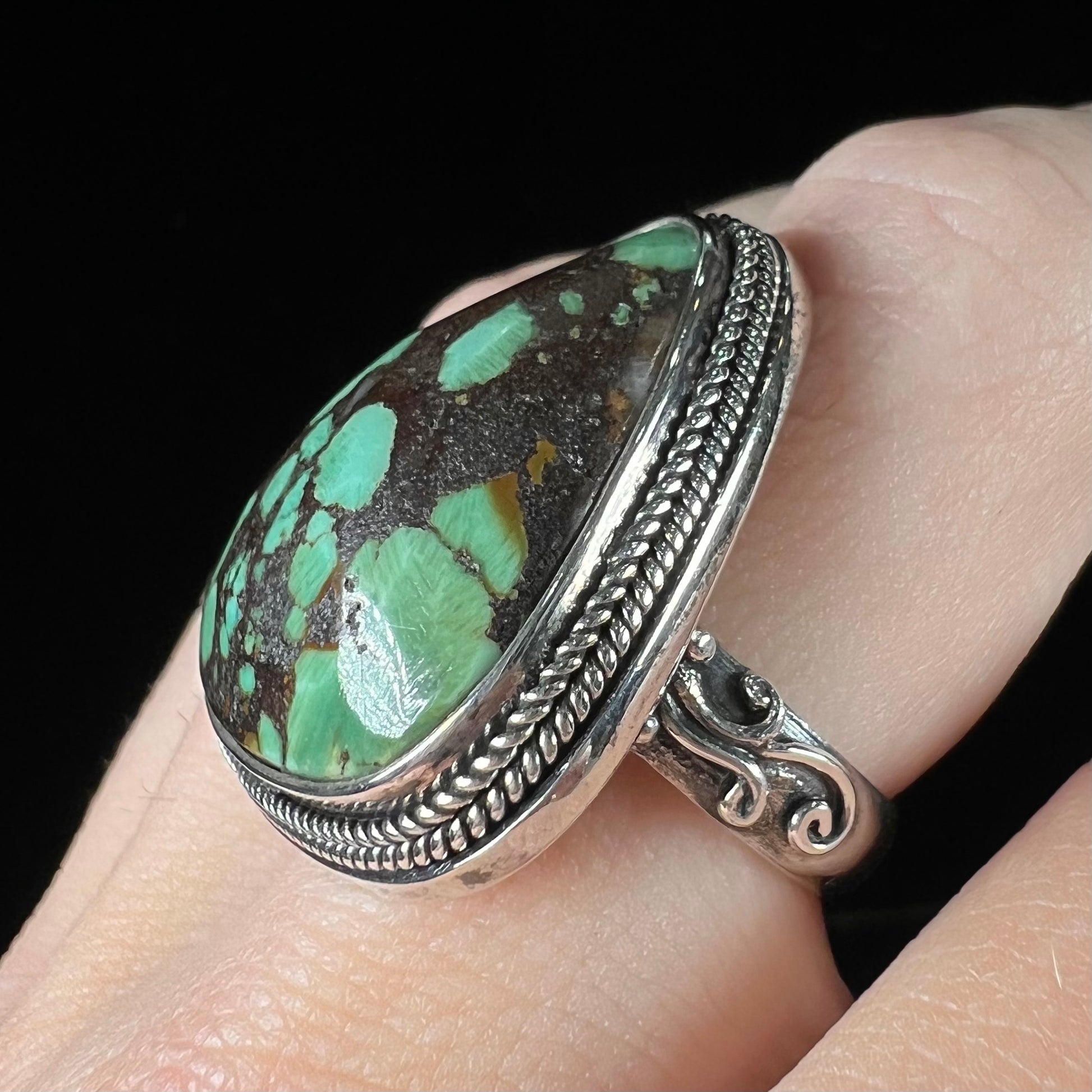 A sterling silver ring bezel set with a green spotted turquoise stone from Carico Lake, Nevada.