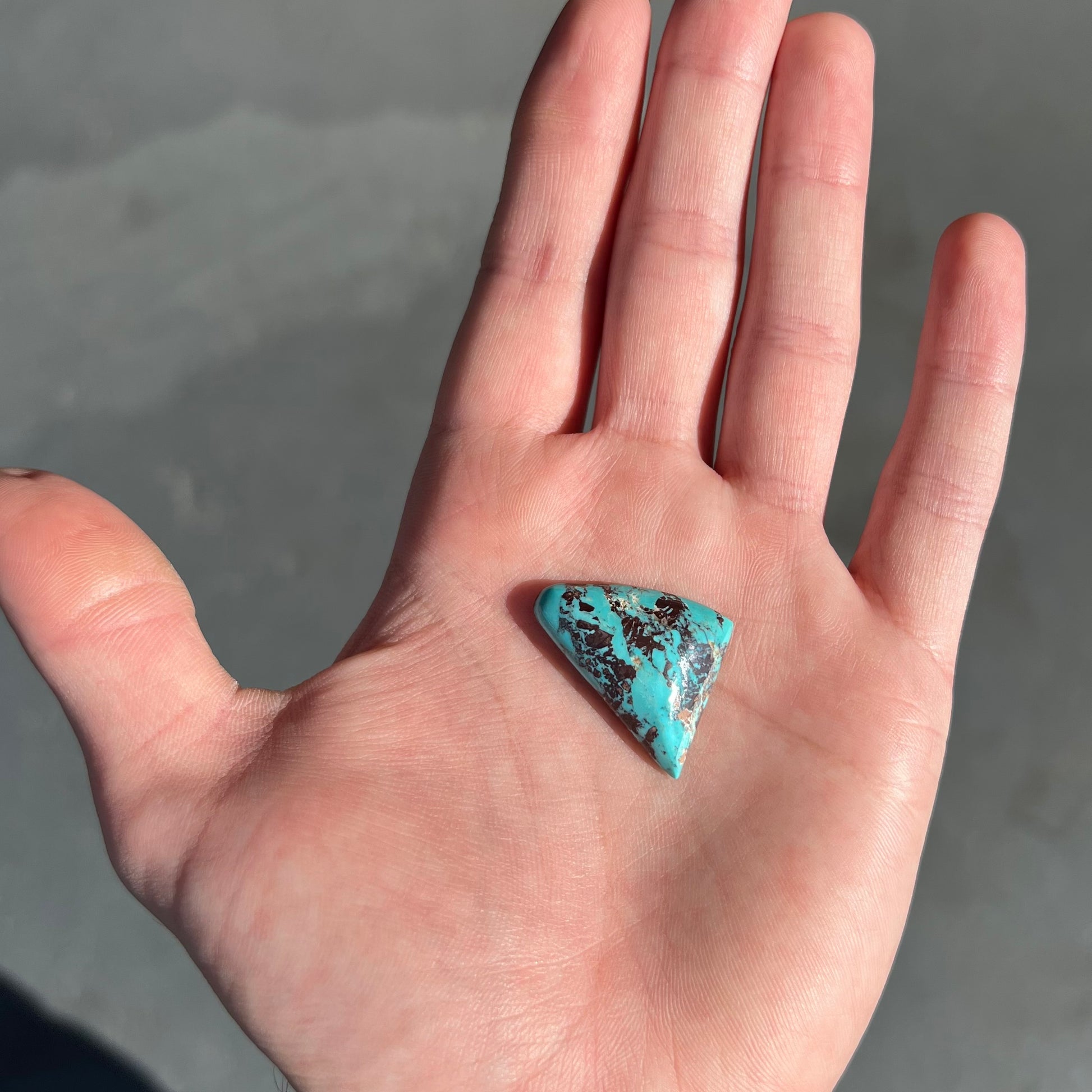 A triangular cabochon cut blue turquoise with red matrix from Mohave County, Arizona.