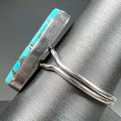 A handmade silver turquoise ring inlaid with six pieces of Sleeping Beauty turquoise.  The back of the ring is signed "FT".