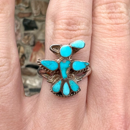 A sterling silver and turquoise inlay ring.  The ring is in the shape of a Native American thunderbird.