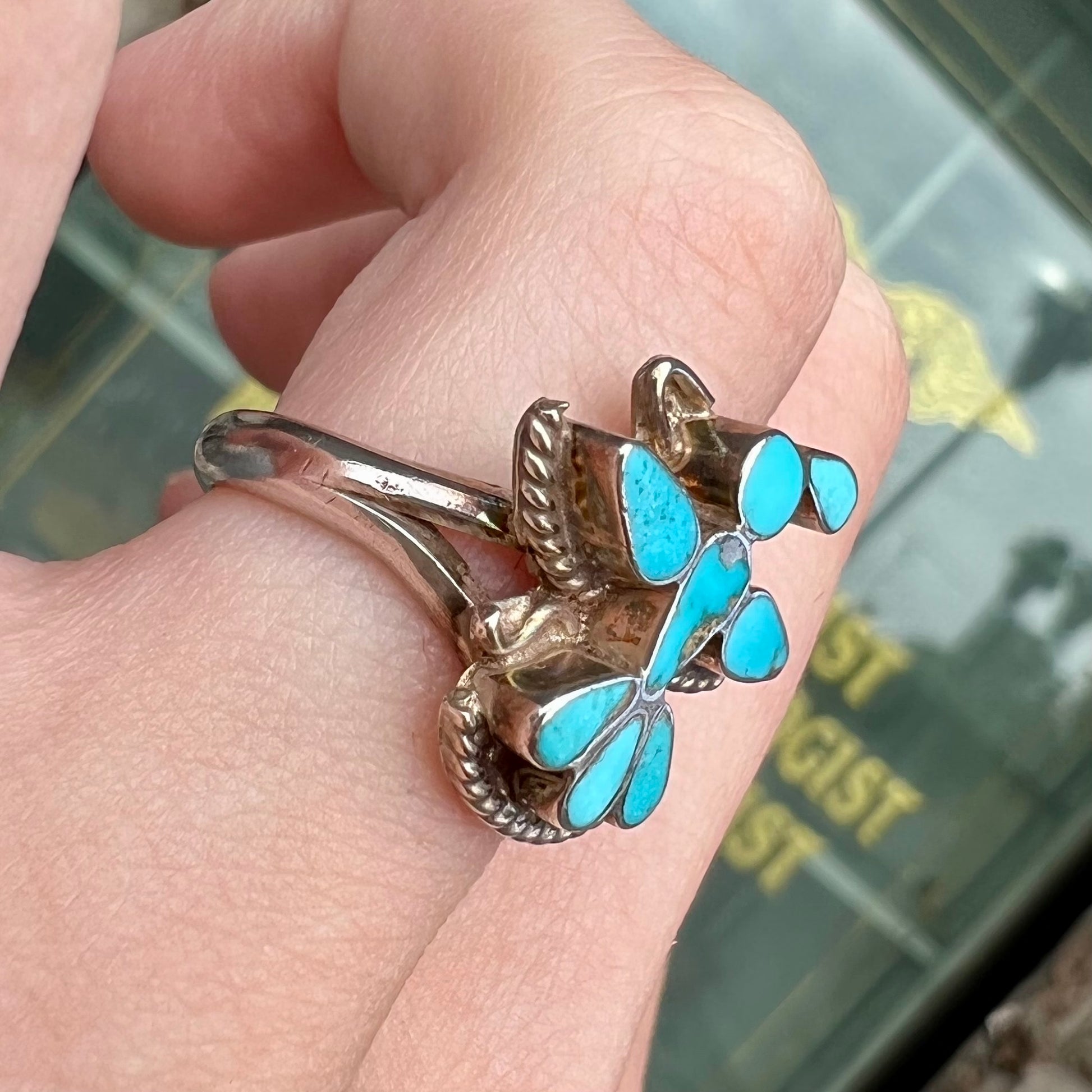 A sterling silver and turquoise inlay ring.  The ring is in the shape of a Native American thunderbird.