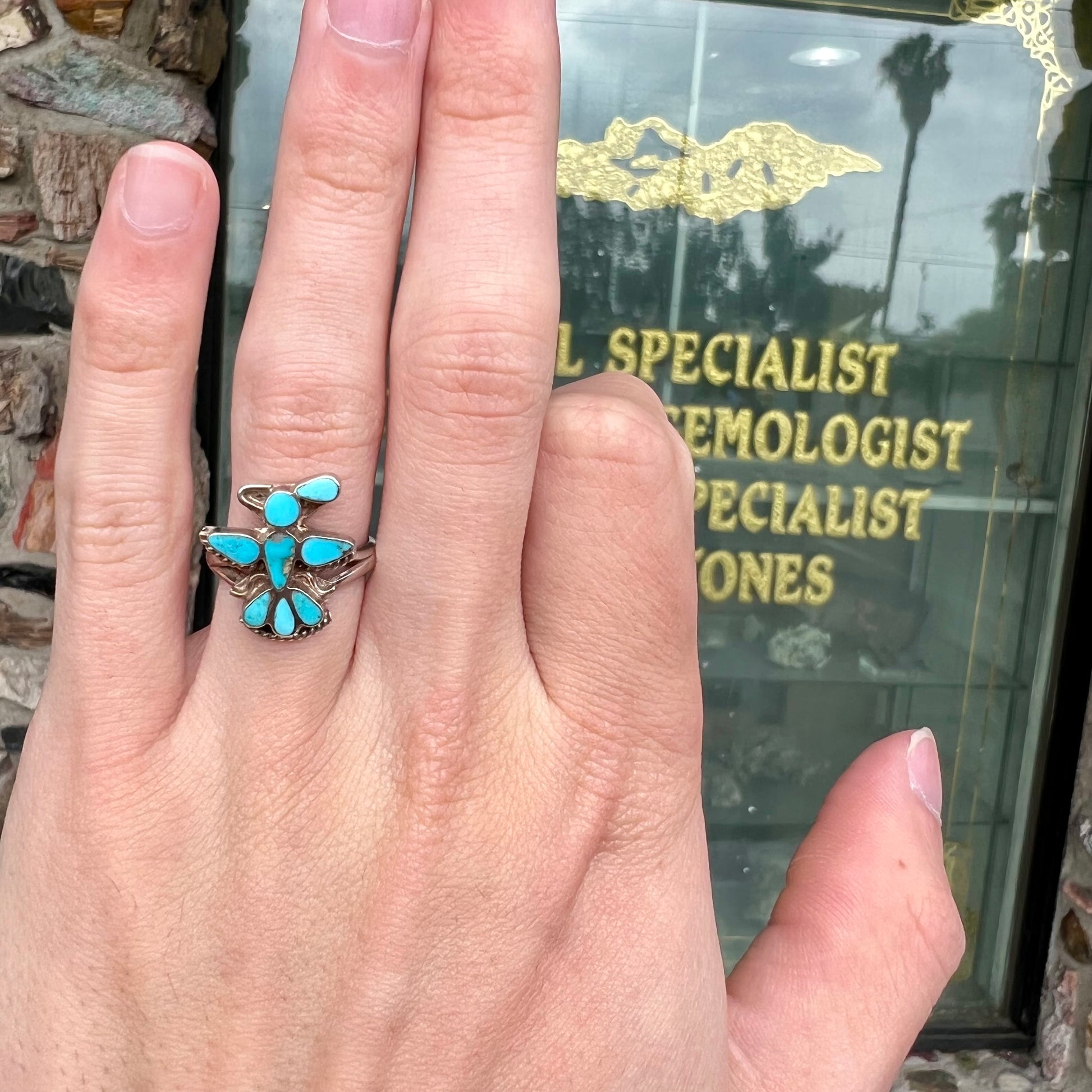 A sterling silver and turquoise inlay ring.  The ring is in the shape of a Native American thunderbird.