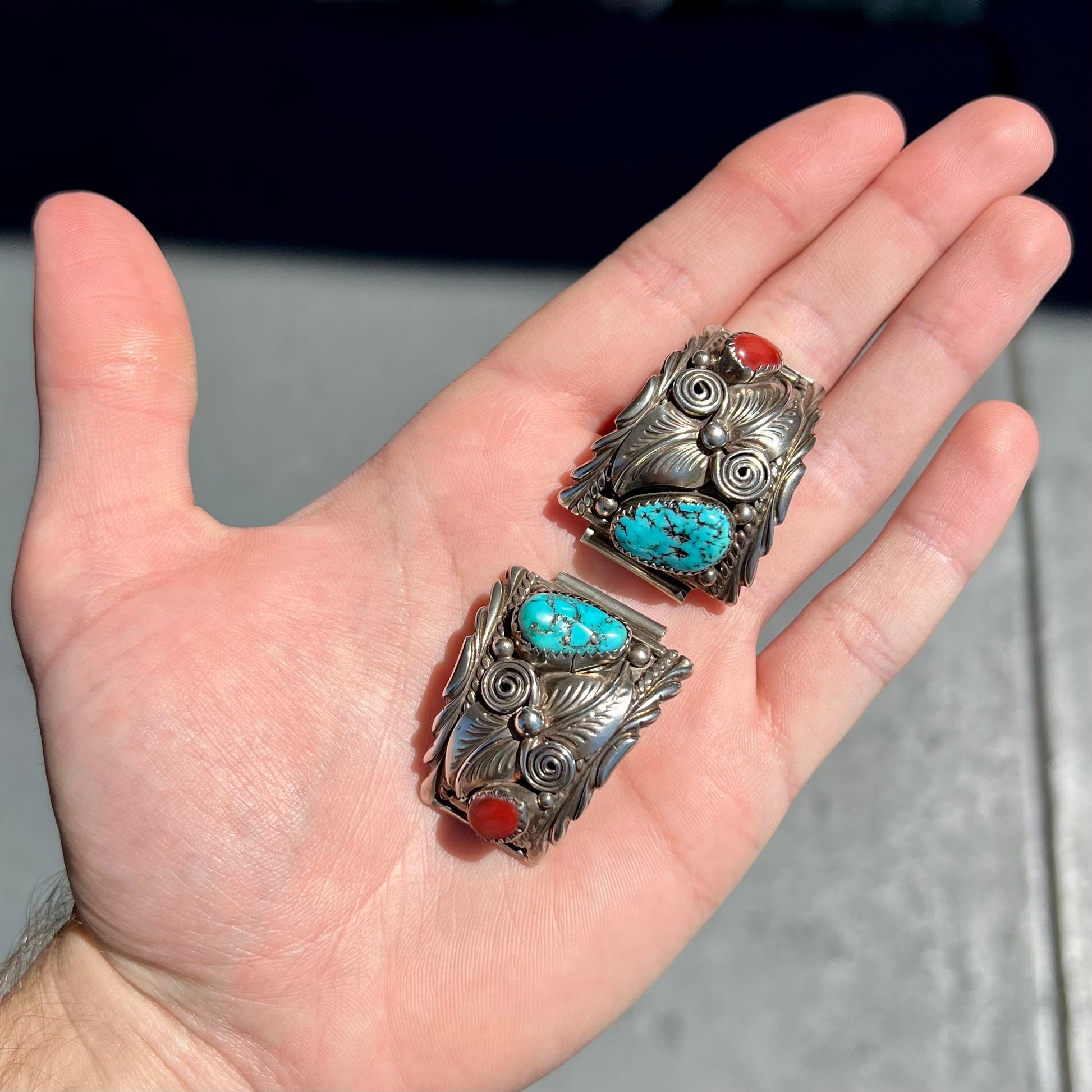 A pair of sterling silver watch cuffs set with turquoise and coral stones.