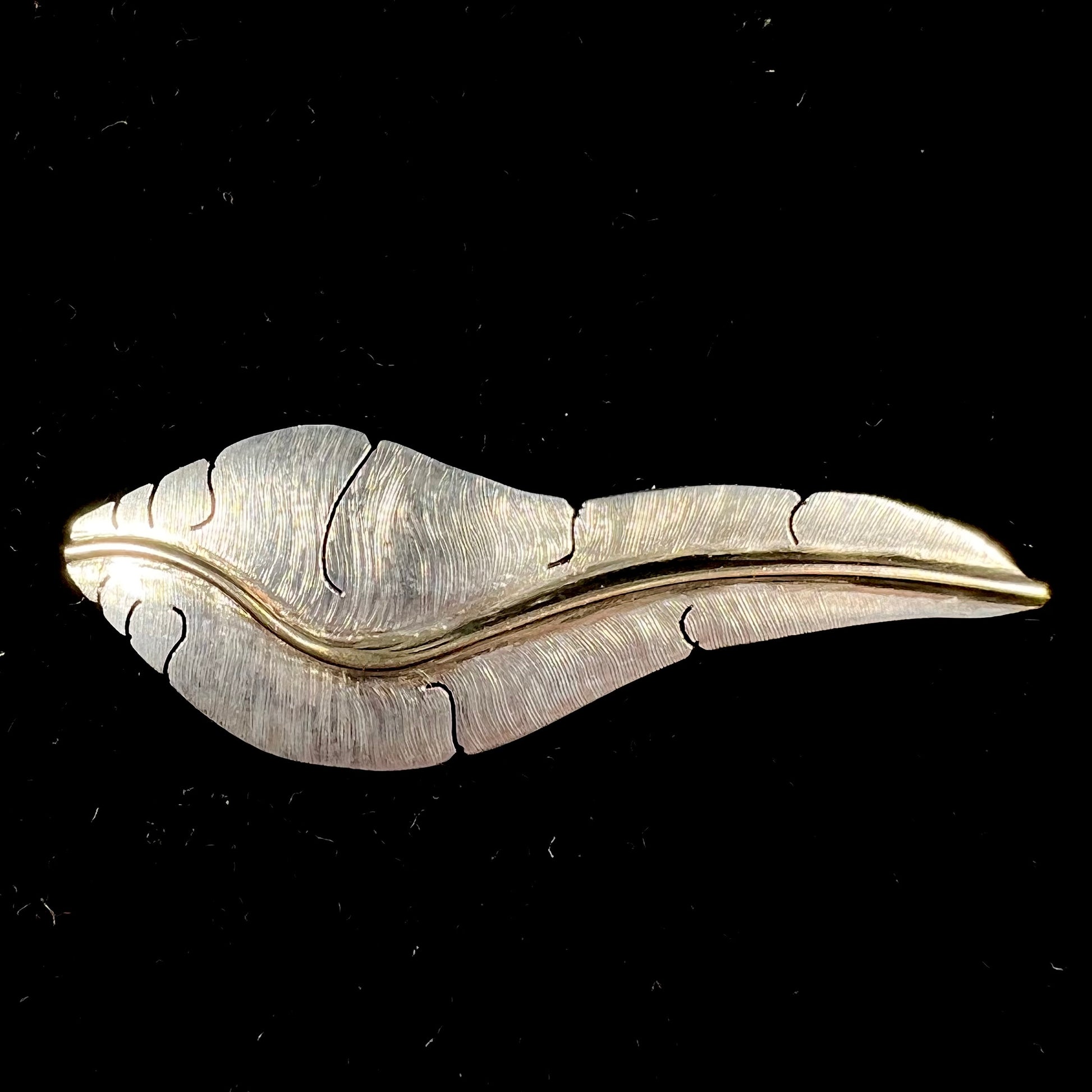 A two-tone silver and gold feather pin, handmade by Isleta Pueblo Indian artist, Michael Kirk.