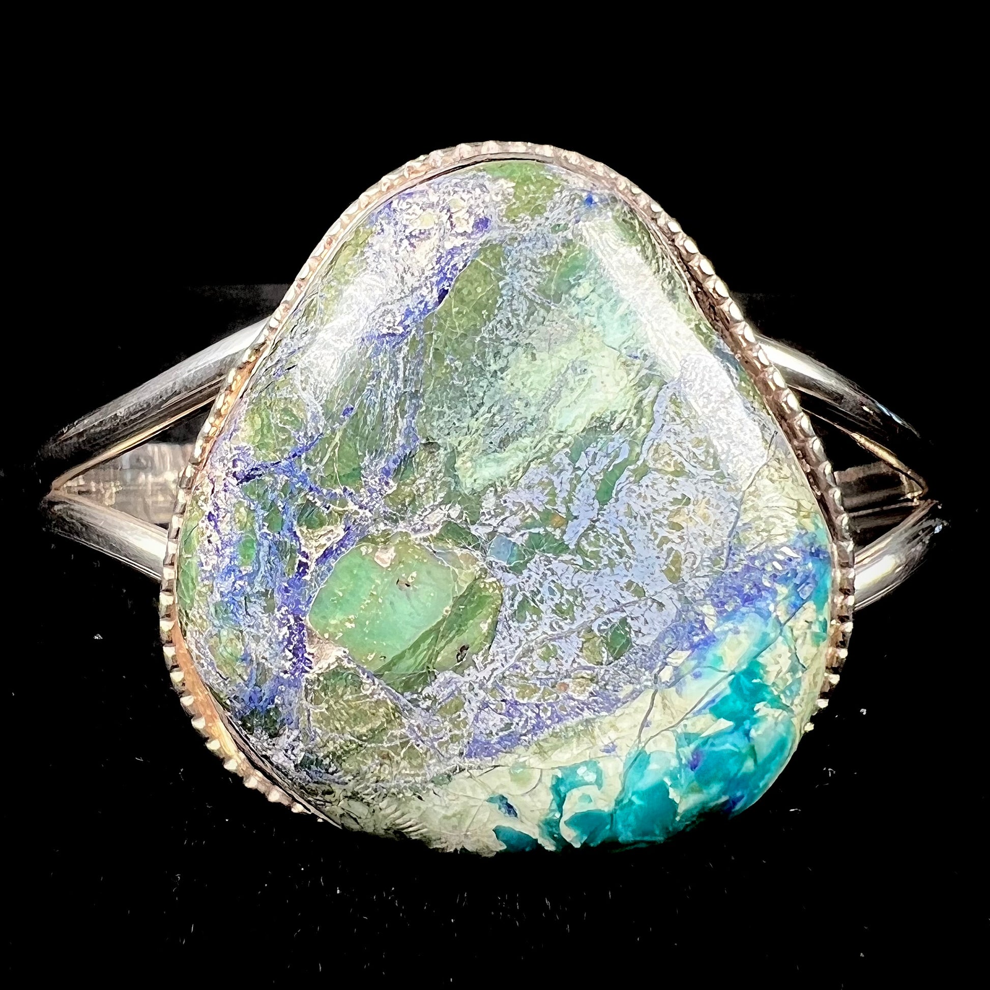 A handmade sterling silver cuff bracelet set with a single stone formed from variscite, chrysocolla, and azurite.
