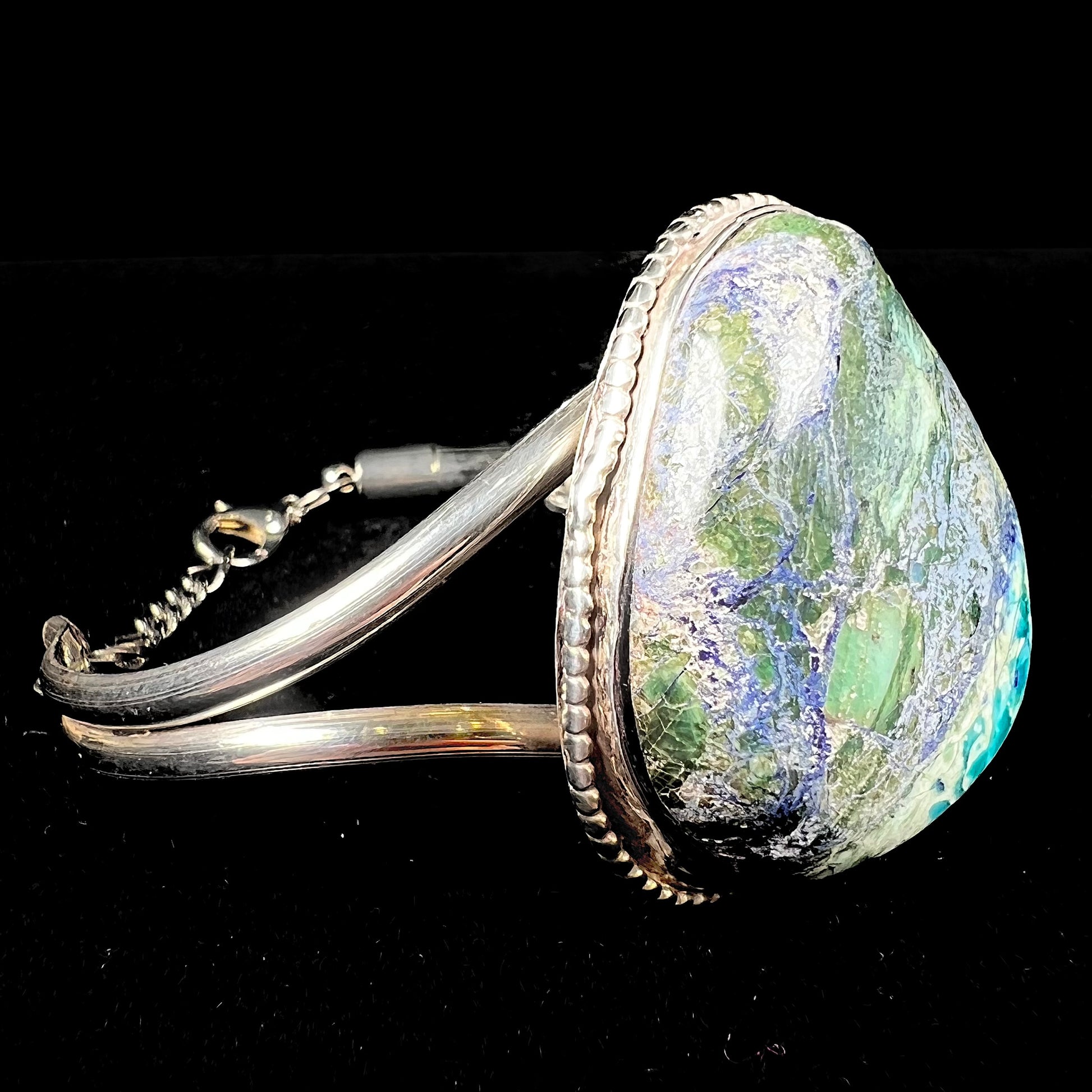 A handmade sterling silver cuff bracelet set with a single stone formed from variscite, chrysocolla, and azurite.