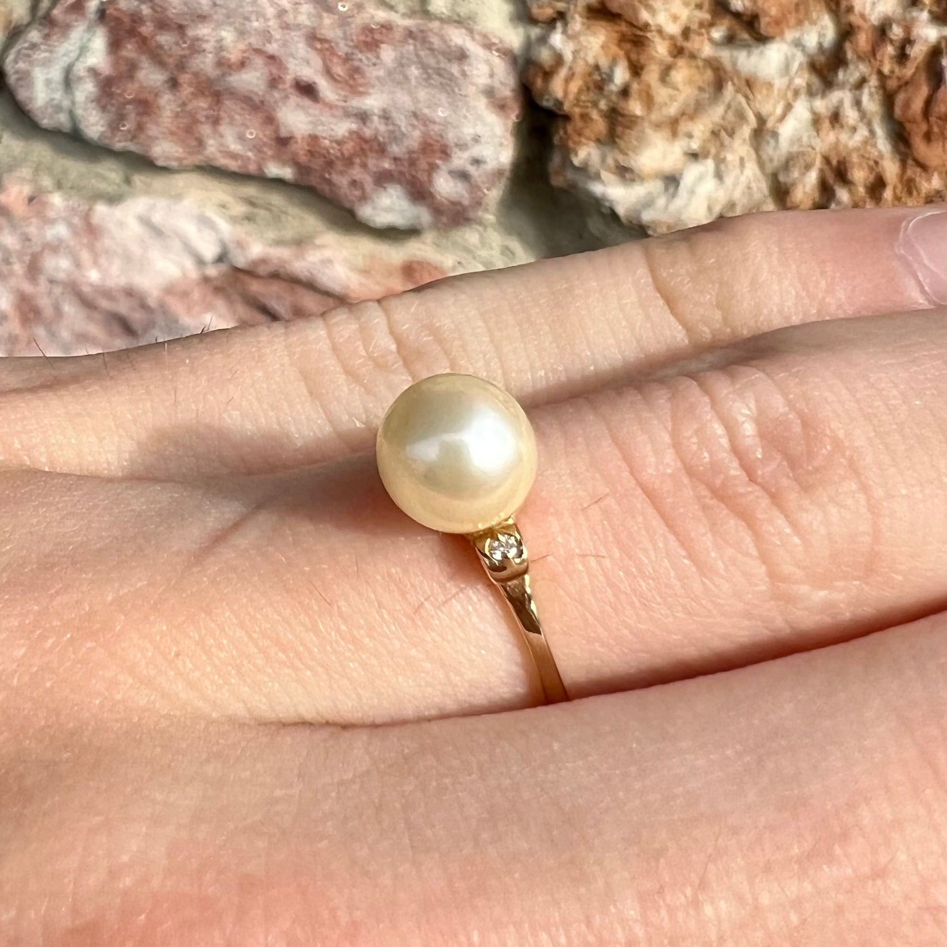 A simple, vintage, yellow gold pearl ring set with two side diamonds.