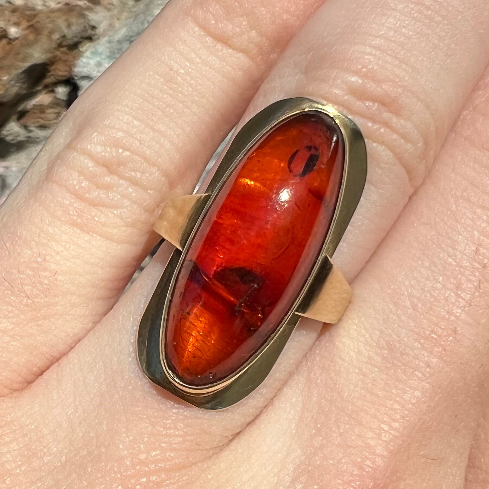 An oval cabochon cut Baltic amber stone set in a yellow gold ring and stamped "AMBER GUILD."