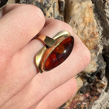 An oval cabochon cut Baltic amber stone set in a yellow gold ring and stamped "AMBER GUILD."