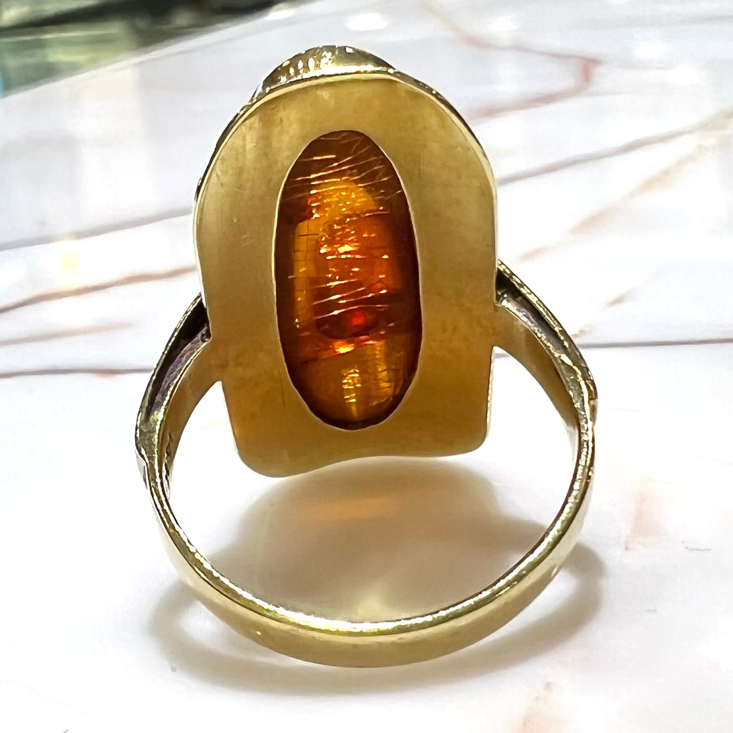 An oval cabochon cut Baltic amber stone set in a yellow gold ring and stamped "AMBER GUILD."