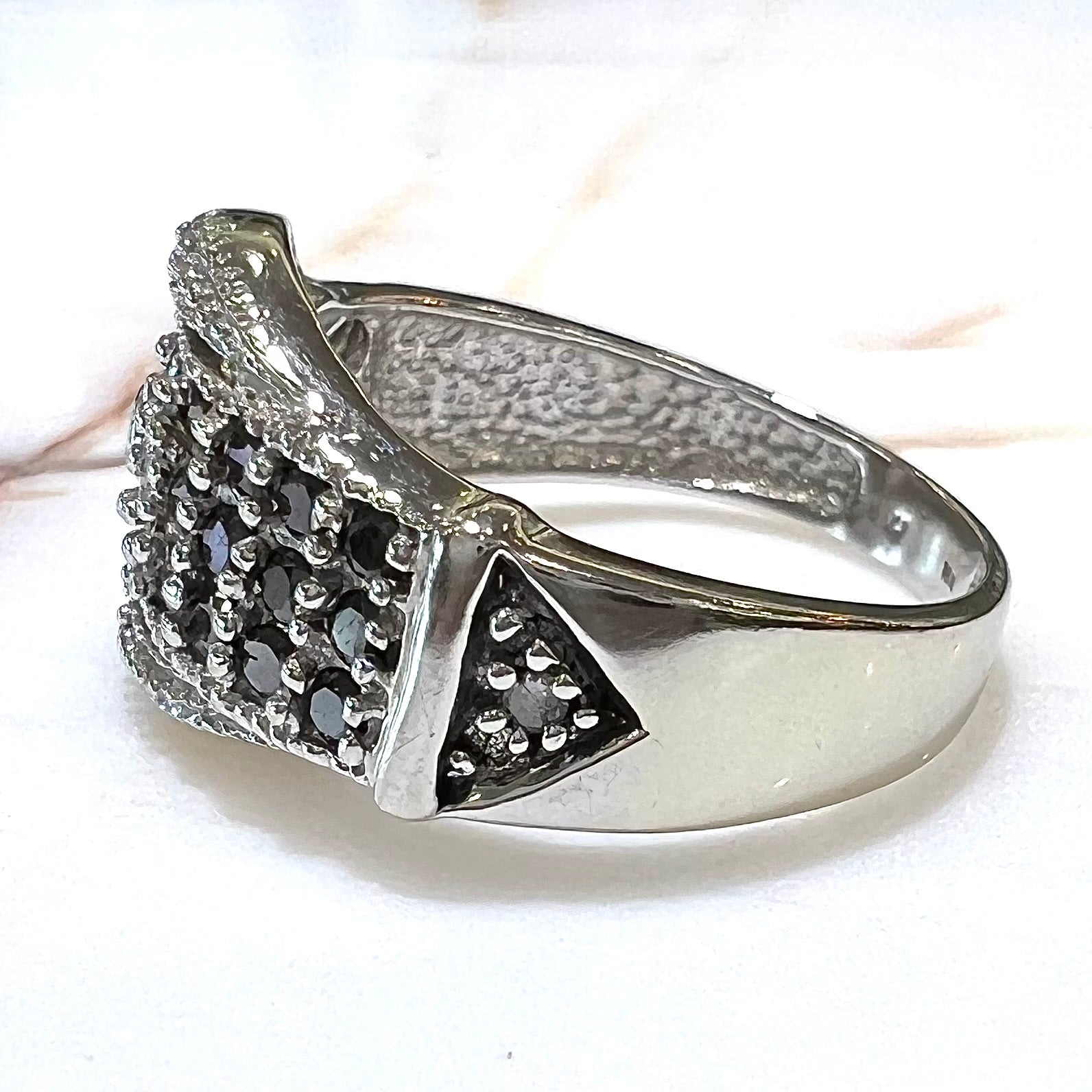 A white gold buckle ring pave set with round black and white diamonds.