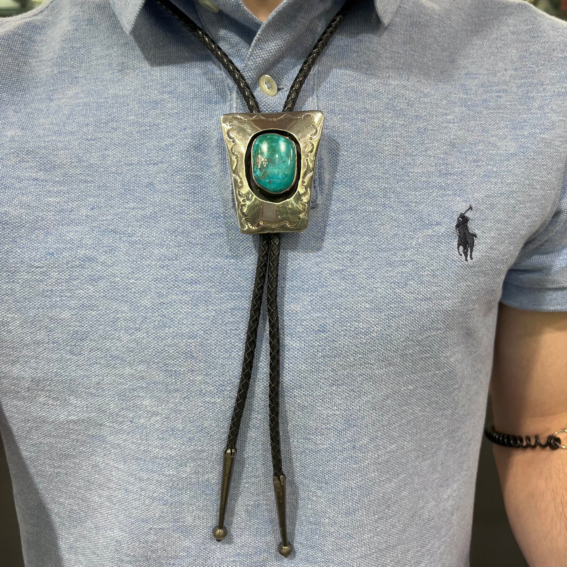 A vintage sterling silver Navajo bolo tie set with Morenci turquoise, handmade by artist Delvin Nelson.
