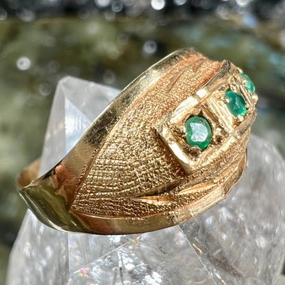 A 1920's style yellow gold three stone round cut emerald ring.