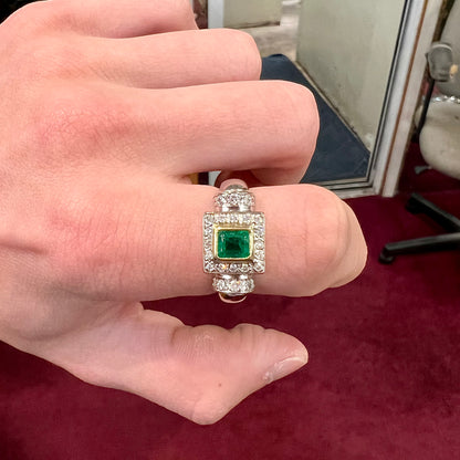 A two tone gold emerald and diamond halo ring.