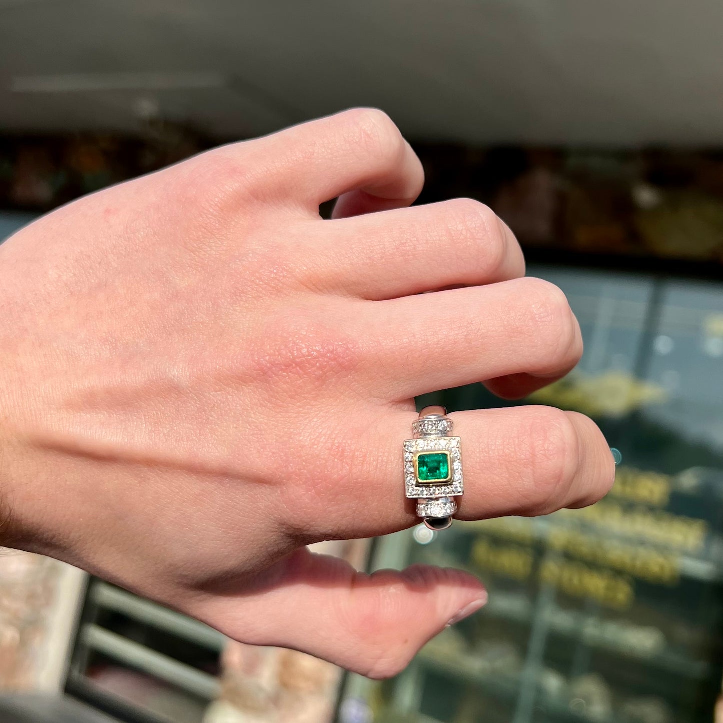 A two tone gold emerald and diamond halo ring.