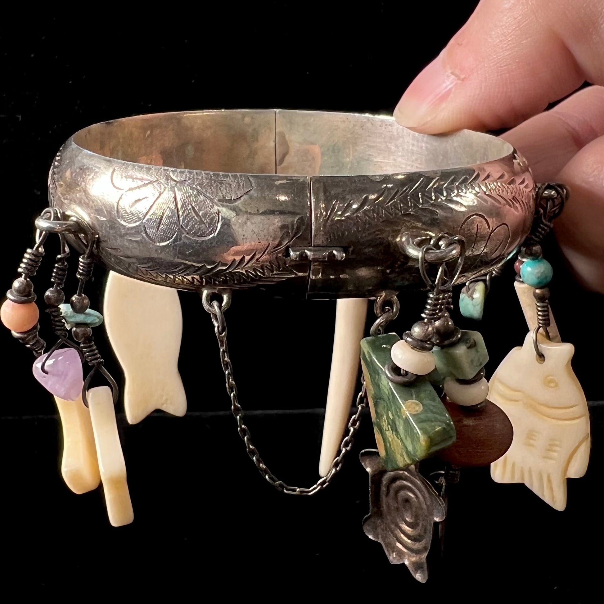A Native American sterling silver bangle bracelets attached with carved bone, gemstone, and silver charm fetishes.
