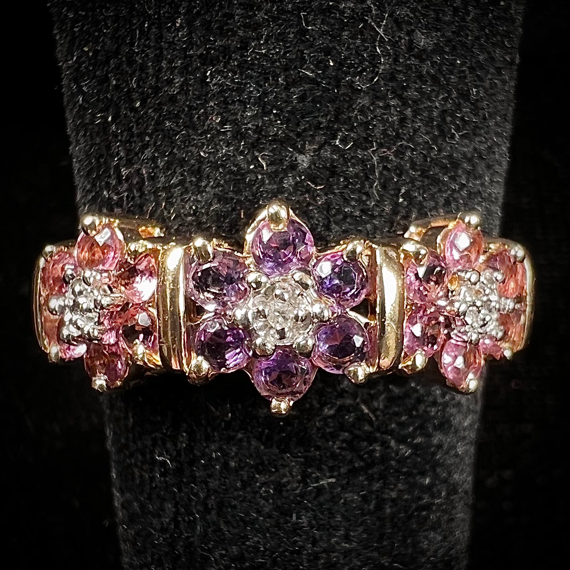 A vintage ladies' flower ring set with set with amethyst and pink tourmaline petals with a diamond center stone.
