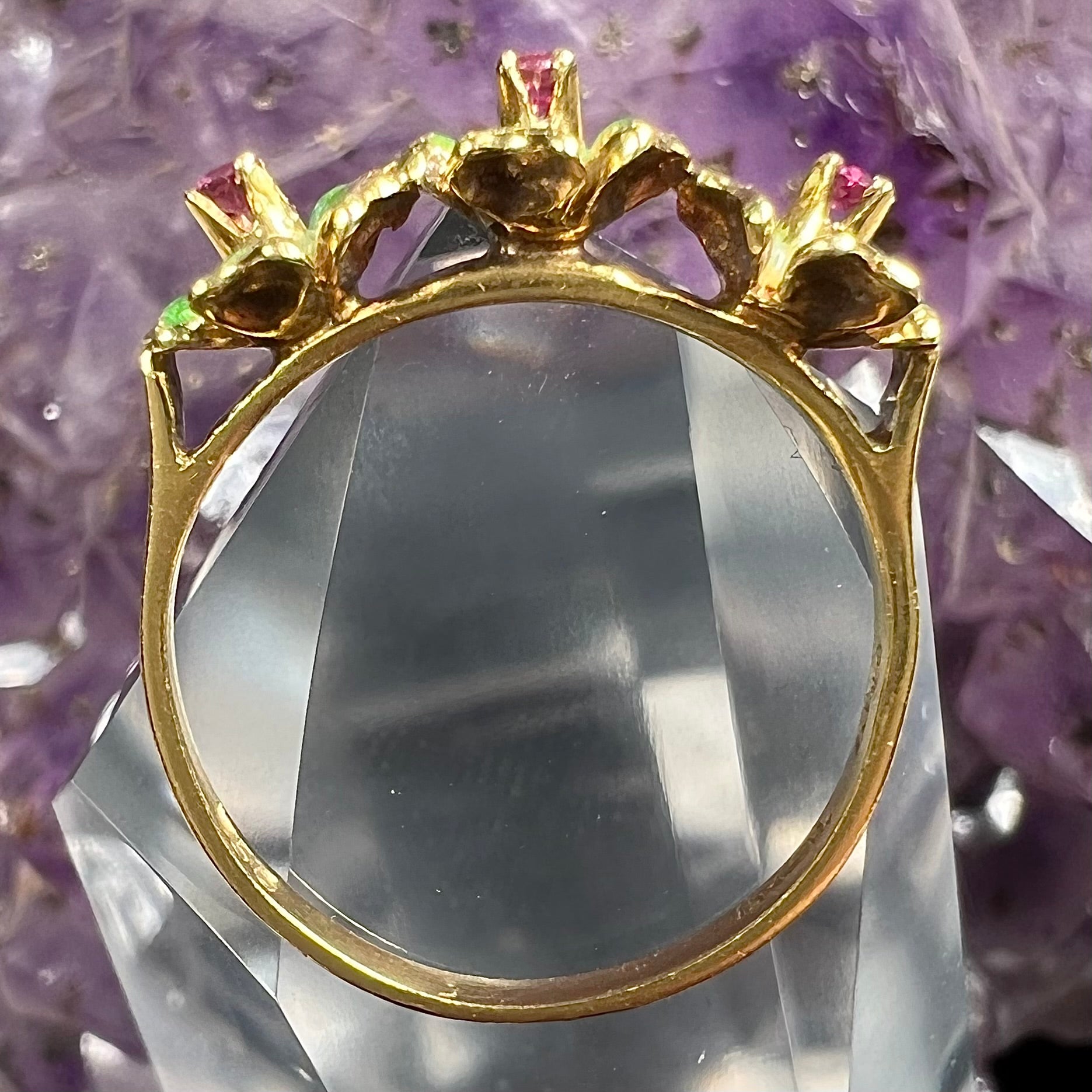 A gold ladies' ring in the motif of three flowers set with round ruby centers and green enameled petals.