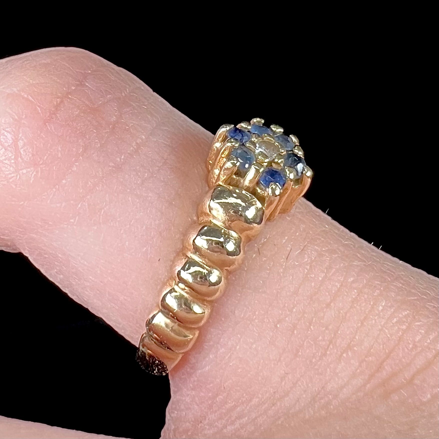 A ladies' yellow gold cluster ring set with round blue sapphires and a round diamond.