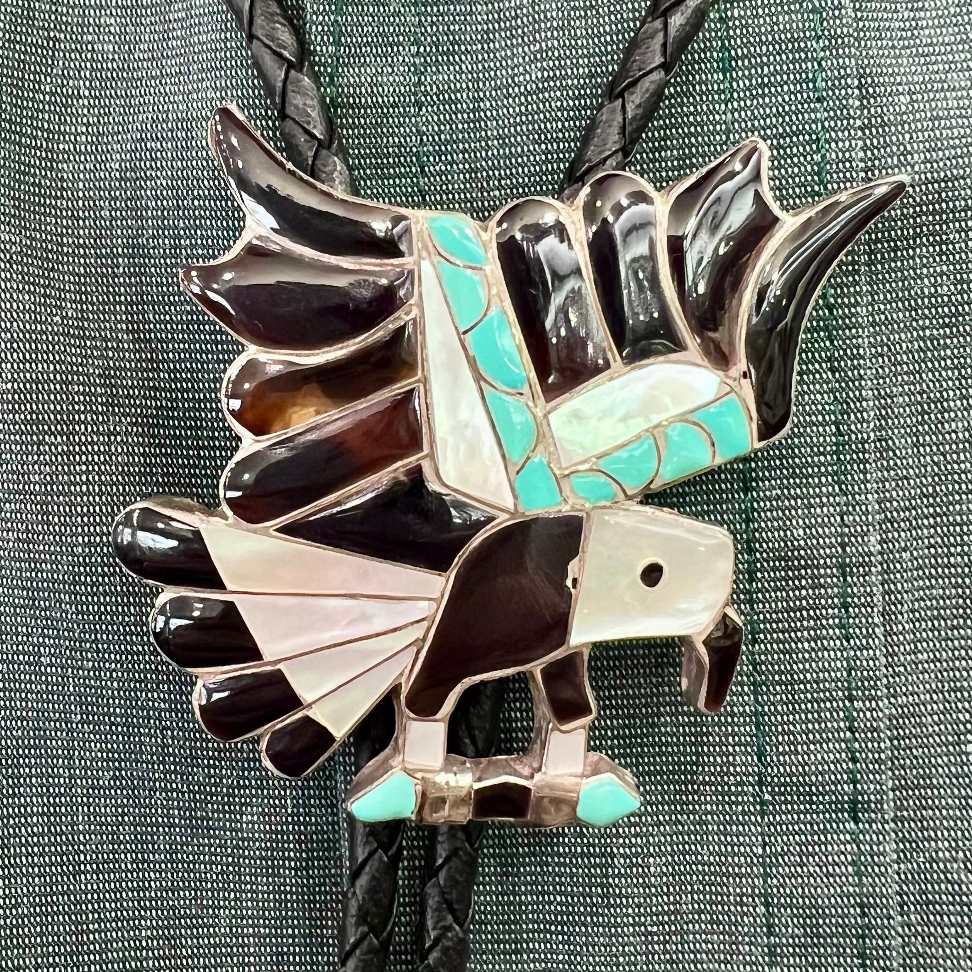 A sterling silver Zuni Indian-made bolo tie featuring the motif of three flying eagles inlaid with natural stones.
