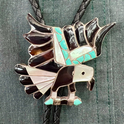 A sterling silver Zuni Indian-made bolo tie featuring the motif of three flying eagles inlaid with natural stones.