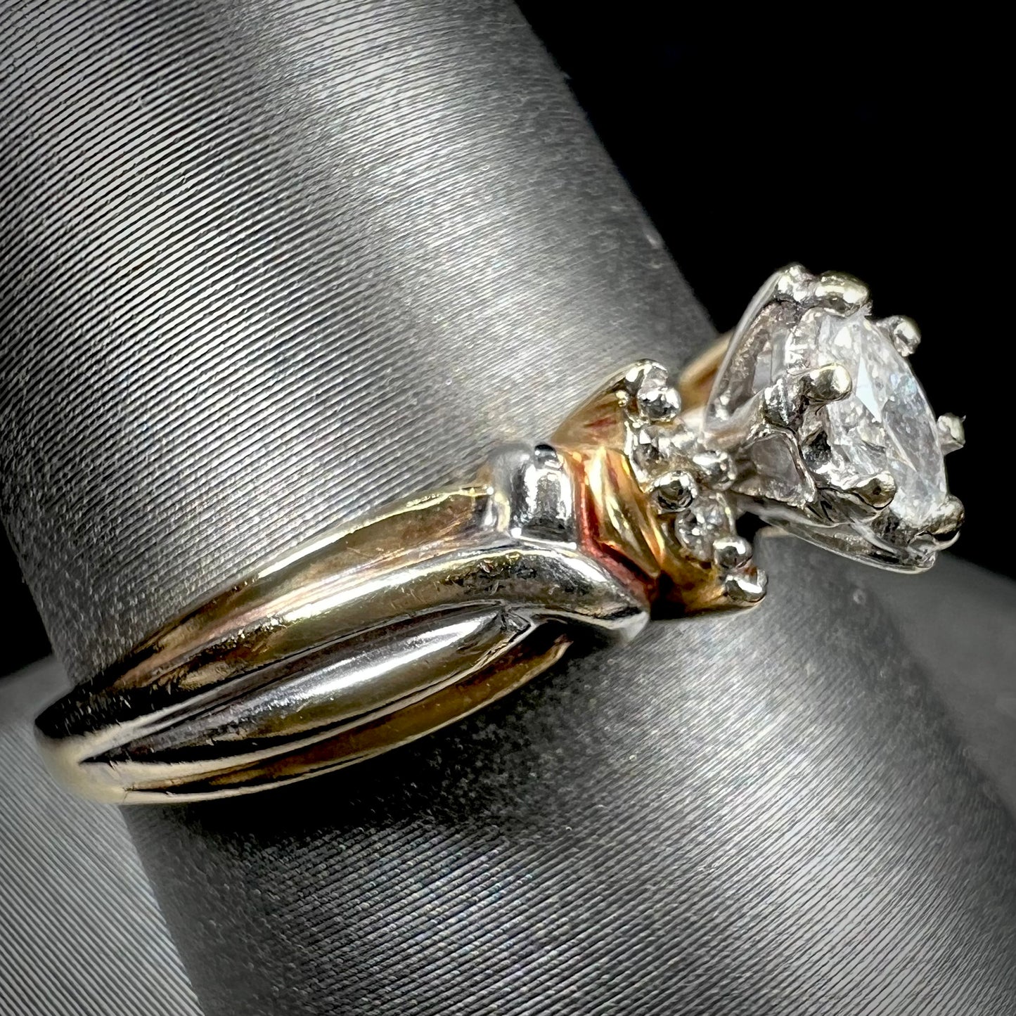A ladies' two-tone white and yellow gold marquise cut diamond enagagement ring.  There are round diamond accents.