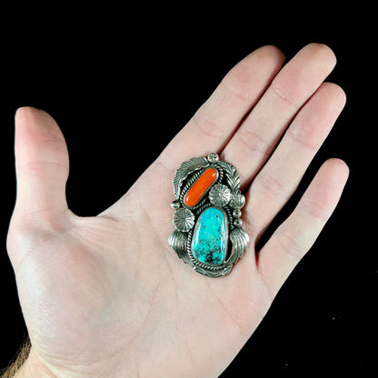 A sterling silver, 1970's Navajo pendant set with Kingman turquoise and coral stones, handmade by artist Angela Lee.