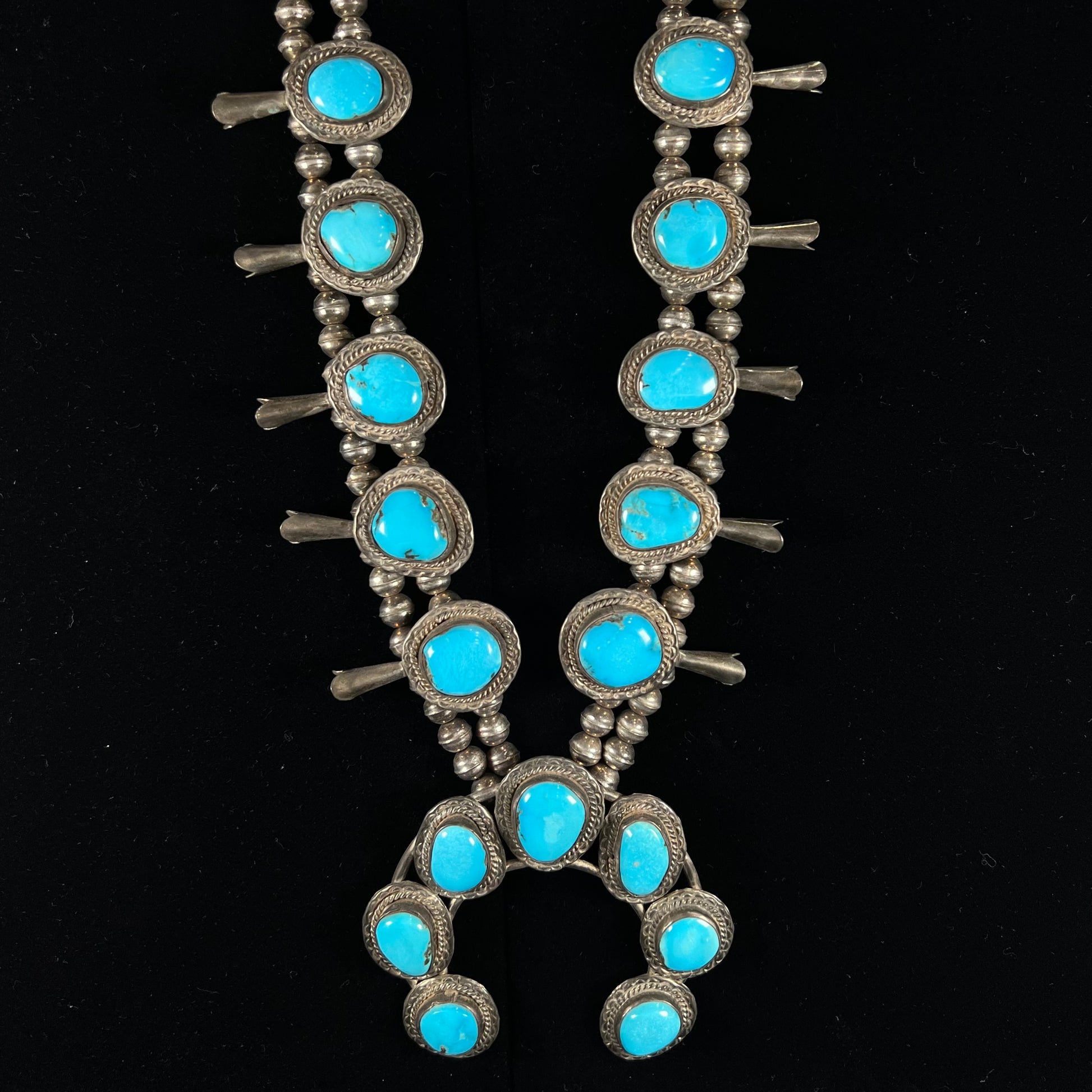 A handmade, sterling silver, Navajo Sleeping Beauty turquoise squash blossom necklace.