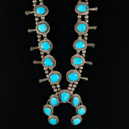 A handmade, sterling silver, Navajo Sleeping Beauty turquoise squash blossom necklace.