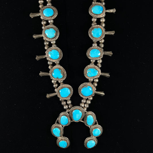 A handmade, sterling silver, Navajo Sleeping Beauty turquoise squash blossom necklace.