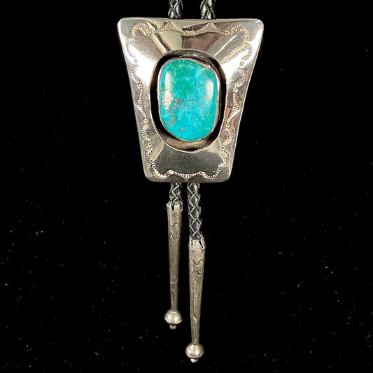 A vintage sterling silver Navajo bolo tie set with Morenci turquoise, handmade by artist Delvin Nelson.