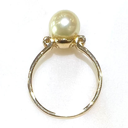 A simple, vintage, yellow gold pearl ring set with two side diamonds.