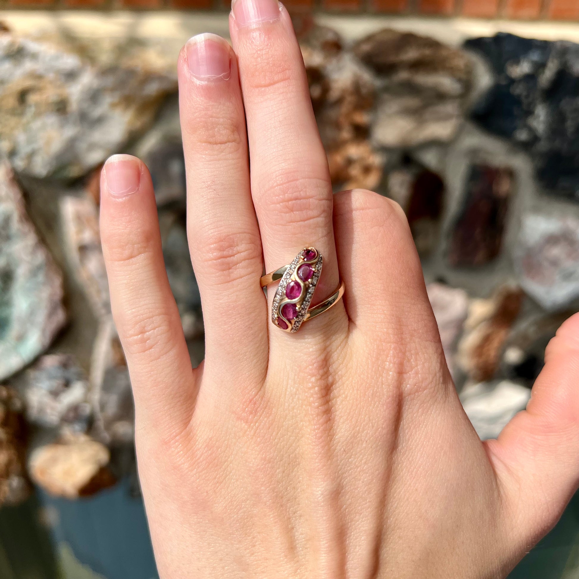 A custom freeform design yellow gold twisted shank ring set with five oval cut rubies and small round diamonds.