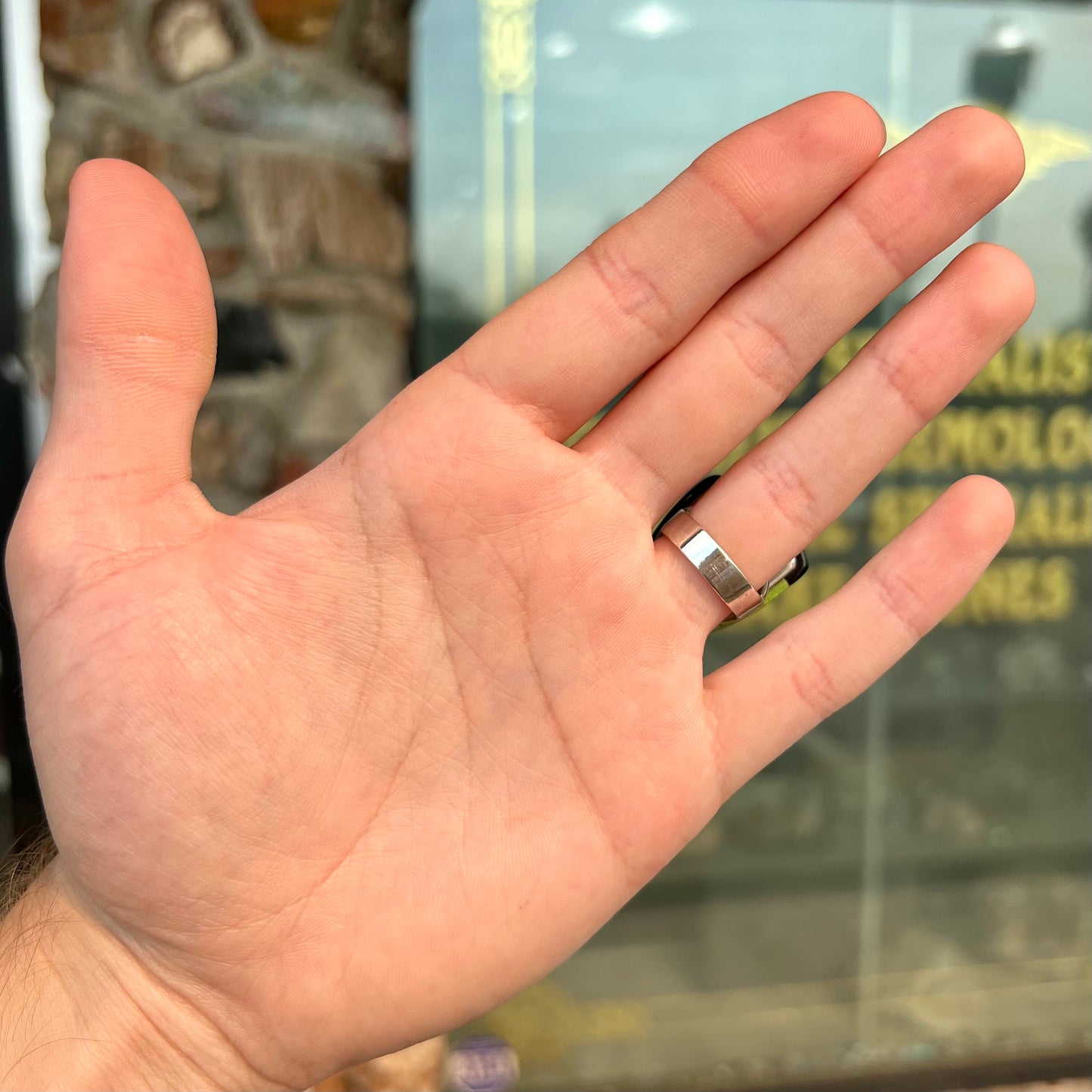 A shield shaped silver ring bezel set with a green gaspeite stone with stone inlaid edges, handmade by artist Benny Armijo.