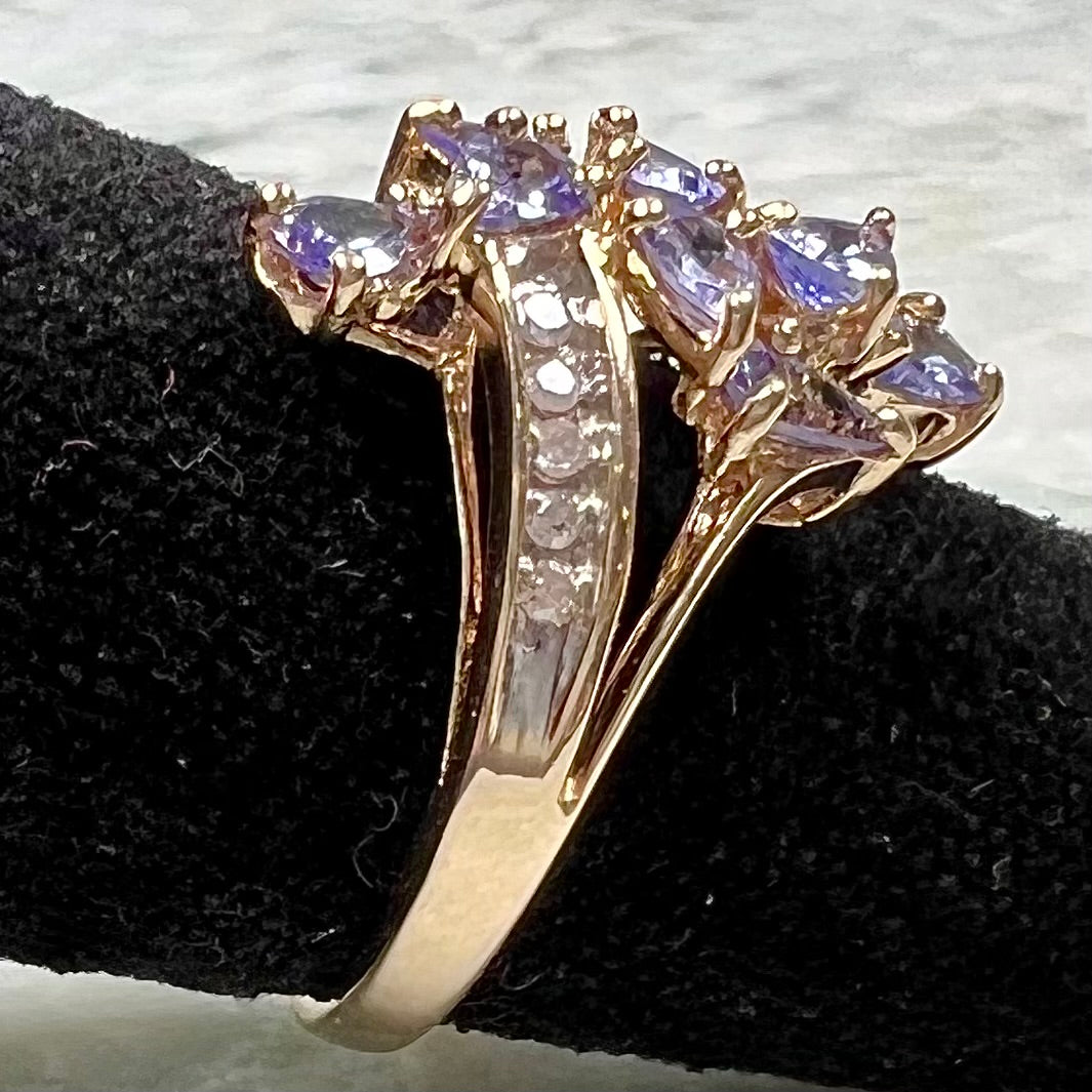 A pear shape tanzanite cluster ring channel set with diamonds in yellow gold.