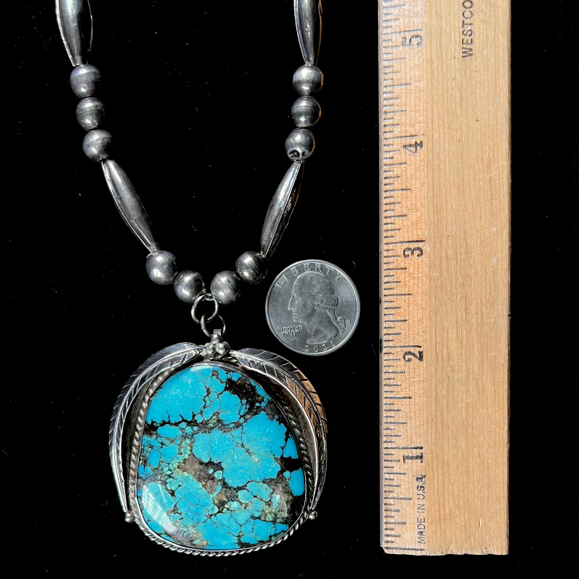 A Navajo style silver beaded necklace set with a Kingman spiderweb turquoise stone.