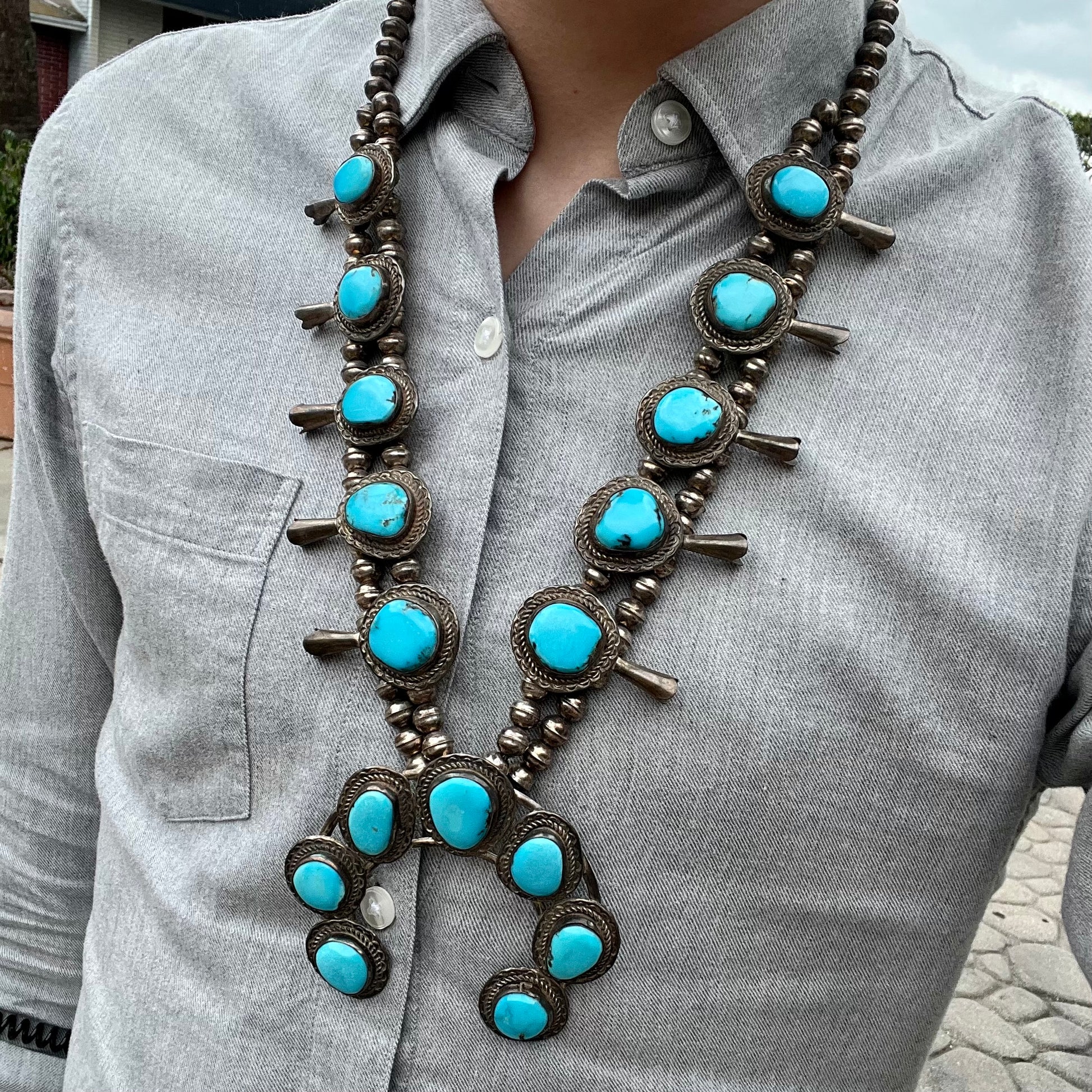A handmade, sterling silver, Navajo Sleeping Beauty turquoise squash blossom necklace.