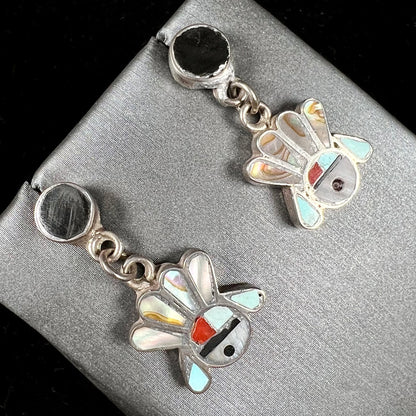 A pair of dangle earrings depicting the motif of Zuni Indian Sunfaces, inlaid with mother of pearl, onyx, turquoise, and coral.