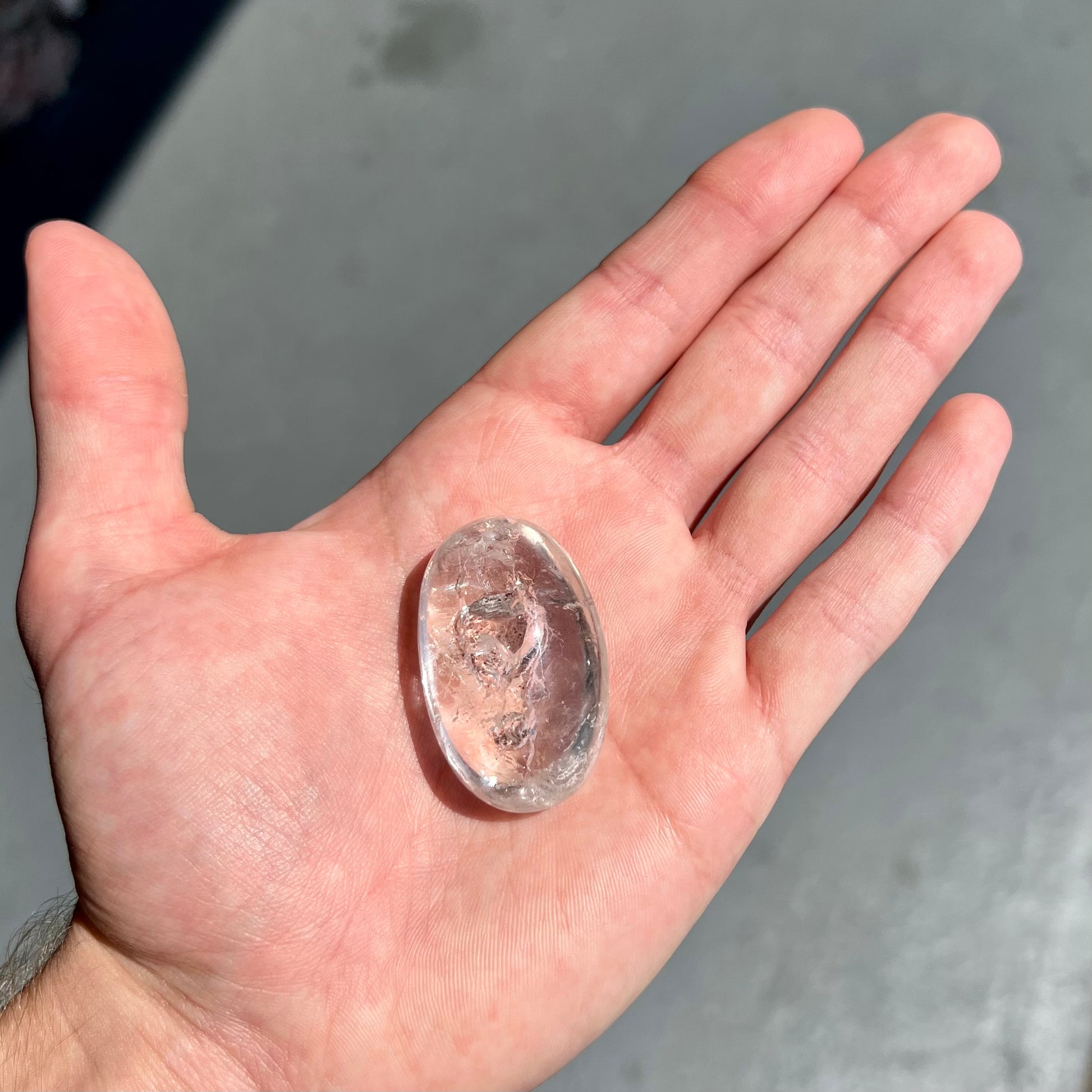 A polished clear quartz with two liquid enhydro inclusions around a solid phantom crystal inclusion.