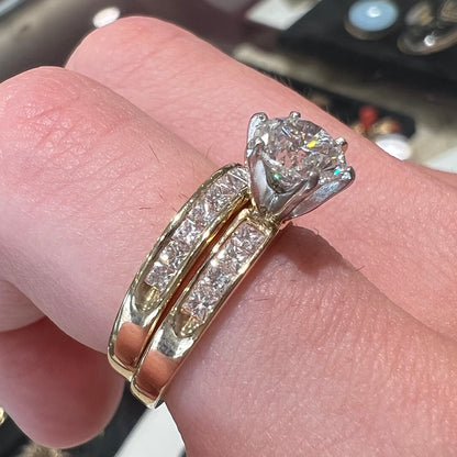 A diamond engagement and wedding ring set.  The center stone is a 1 carat round diamond, and the side stones are channel set princess cut diamonds.